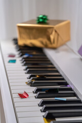 Golden gift box with green bow on piano keys for festive celebration © Nataliia