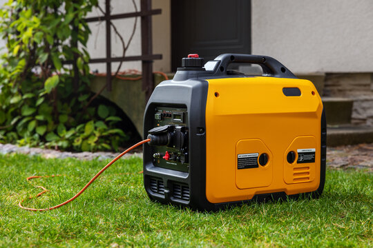 Portable inverter generator working in front of house. Home backup power or outdoor electricity supply