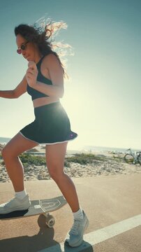 Young woman enjoying a summer day longboarding near the beach