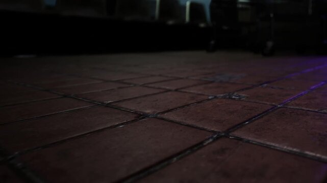 The scene shows a close up view of a rustic tiled floor in a warm, inviting space, hinting at the lively conversations and moments shared here during the evening hours.