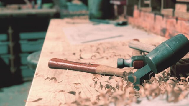 A skilled artisan works diligently in a lively woodshop, surrounded by tools and wood shavings. The warm light highlights the craftsmanship and attention to detail in this creative space.