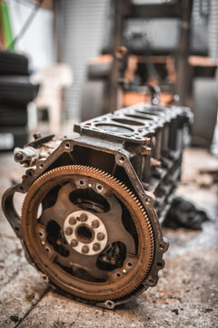 Close-up of a rusty engine block and flywheel in a workshop setting