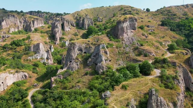 Drone aerial footage passing over the Khndzoresk cave settlement in southern Armenia, showing numerous cave dwellings, vertical rock formations, narrow ravines and dry mountain slopes.
