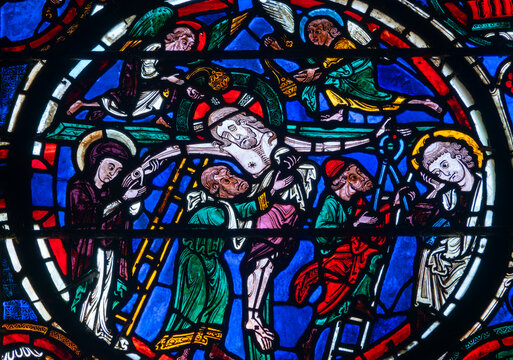 Angels and disciples lower the body of Jesus Christ from the cross in stained glass.