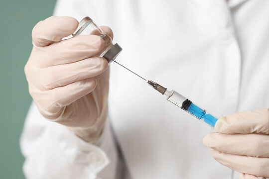 Vaccination and immunization, healthcare professional preparing a medical injection with a syringe and vaccine vial for patient treatment in a clinic