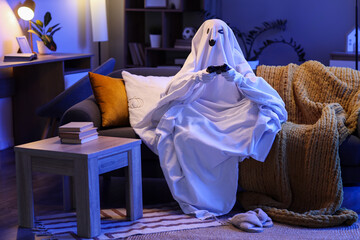 Person dressed as a ghost playing video games on a sofa in a dimly lit living room during halloween night, Fun and entertainment of halloween, with a cozy atmosphere and modern home decor © Pixel-Shot