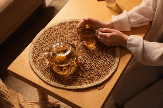 Mindfulness and self care, woman drinking herbal tea at home for relaxation and stress relief in a cozy living room setting with warm evening light