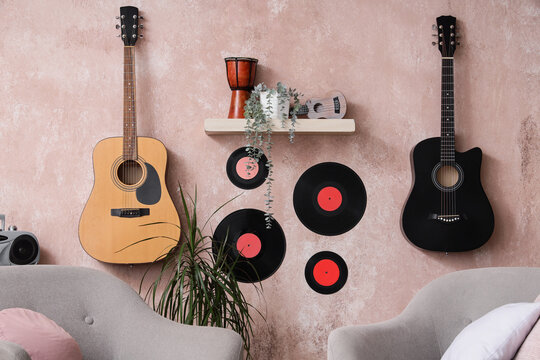 Music hobby and creative lifestyle, acoustic and electric guitars with vinyl records on a textured wall in a cozy living room interior for home decor