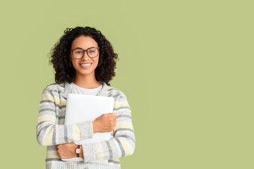 Fototapeta premium Young African-American woman with laptop on green background