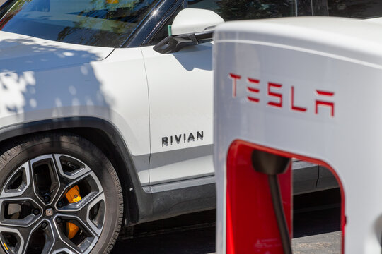 Tesla charger and Rivian electric vehicle captured together at everyday EV charging location within regional transportation network