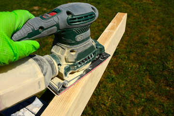 szlifowanie deski ręczną szlifierką elektryczną, szlifowanie deski na altankę, sanding the board with an electric hand sander © kateej