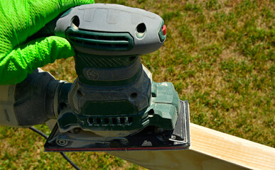 szlifowanie deski ręczną szlifierką elektryczną, szlifowanie deski na altankę, sanding the board with an electric hand sander © kateej