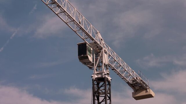 Tower crane boom rising against cloudy sky at construction site