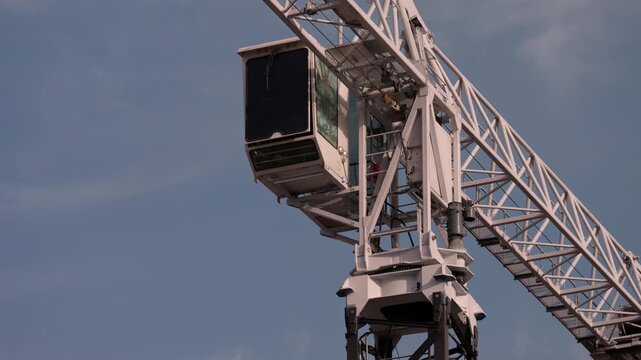 Tower crane operator cabin and lattice boom against blue sky