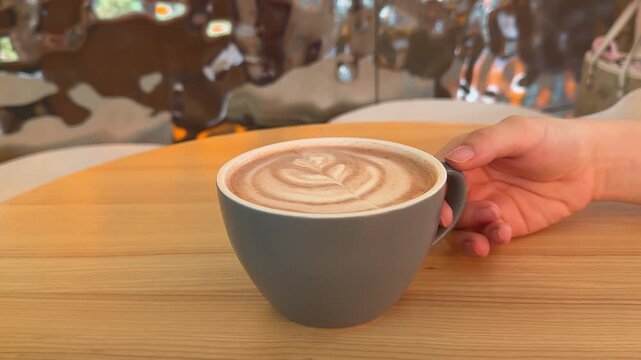 Creamy hot coffee served in a stylish ceramic cup, featuring decorative foam art and creating a cozy cafe atmosphere for a relaxing morning break.