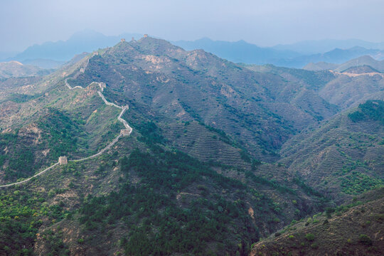 Aerial view of Simatai section of Great Wall of China in its original, un-restored state. Traversing Stone walkway stretches across mountain ridge surrounded by rolling hills, Beijing, China