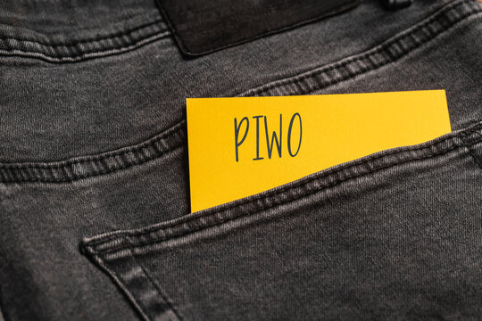 Yellow card with handwritten word Piwo sticking out of black jeans back pocket, close up photo