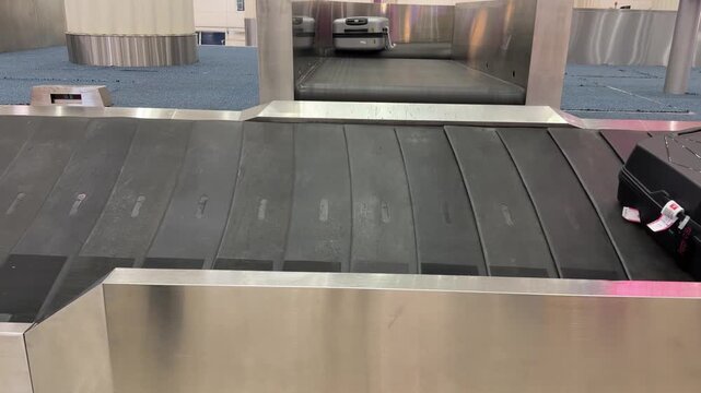 Passenger suitcases on baggage carousel inside modern airport terminal, representing air travel, tourism and luggage collection after journey, shot handheld. High quality 4k footage