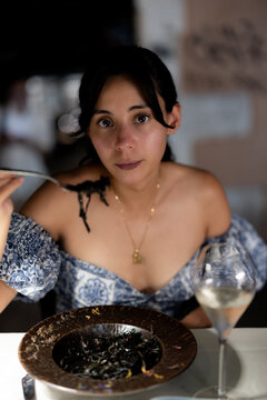Woman tasting squid ink pasta at a restaurant in Venice