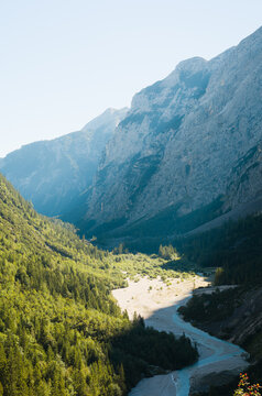 Vertical view of deep alpine valley with riverbed beneath massive mountain peaks