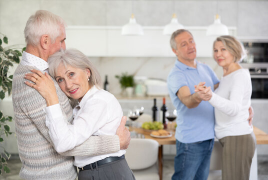 Mature married couple perform slow pair dance during holiday, have fun, move with unhurried music in dining room. Family event is held with romantic music and slow dancing