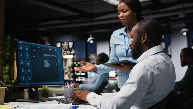 Black IT engineers develop an app and software algorithm on a PC late at night, using digital tools for script engineering and coding in the office.