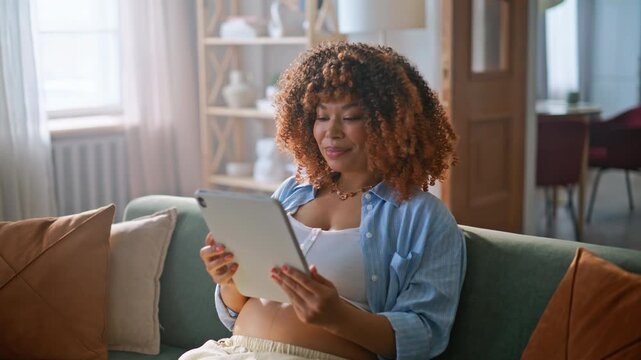 Pregnant woman putting tablet aside touching belly. Expectant mom relaxing sofa.