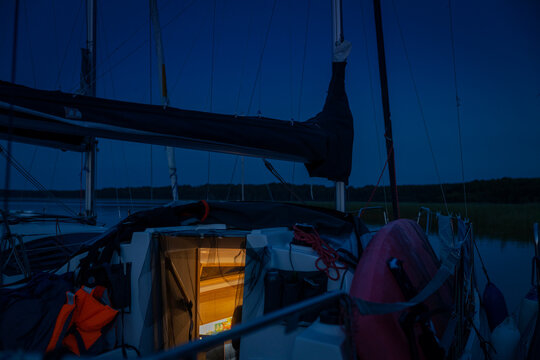 Illuminated Sailboat Cabin Interior at Night Docked in Wilderness Lake Setting