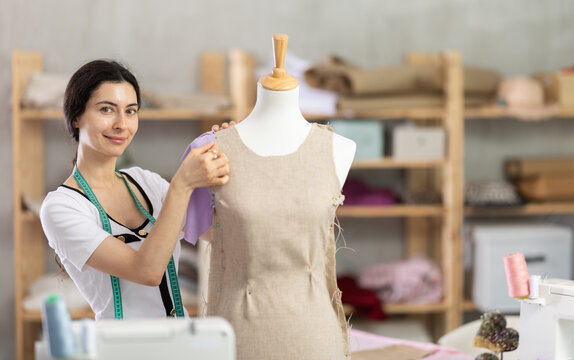 Armenian fashion designer works with fabric on a mannequin, she checks the size of the sample and makes edits. Process of creating clothes