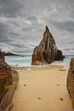 Sharp, central rocky islet midway along Playa de Mexota-A Mixota Beach, at rising tide in a cloudy yet spectacular spring sunrise. Asturias-Spain-013