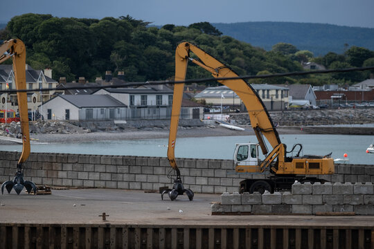 Excavator with clamshell grab working at a waterfront construction site
