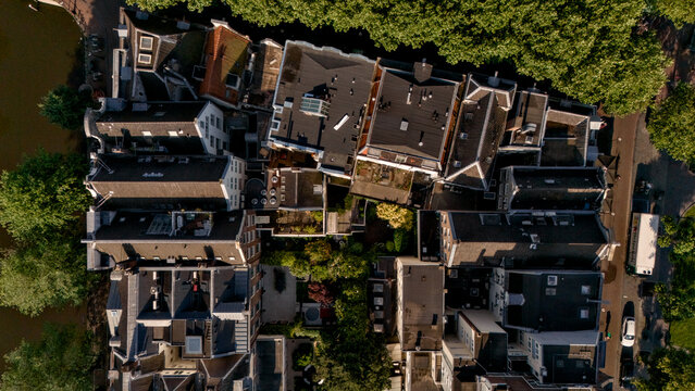 Vertical aerial view of canal-side rooftops and trees in Amsterdam