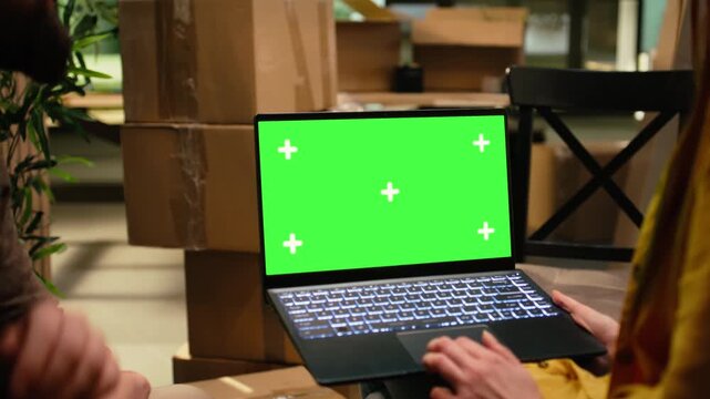 Green screen laptop mockup with a couple discussing layout ideas after moving day, illustrating home ownership, residential settlement and the fun of a fresh start while planning their new interior.