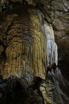 Vertical view of a massive flowstone drapery formation illuminated on the rock face inside the subterranean chambers of Lurgrotte cave in Peggau, Styria, Austria
