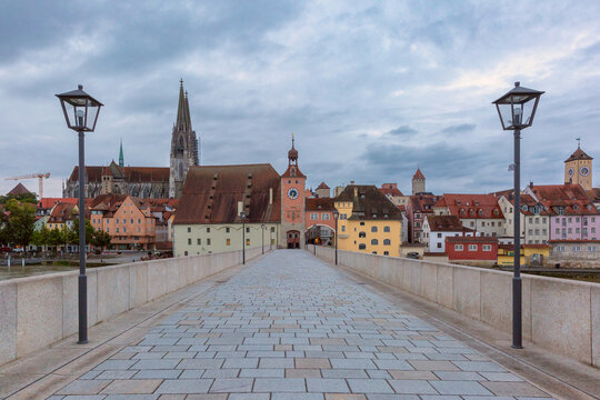 Empty Stone Bridge leading toward the historic architecture and cathedral towers of Regensburg, Bavaria, Germany.