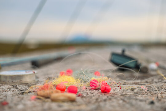 Bright red bobbers and tangled fishing line rest on weathered wooden surface near rods and tackle, showing detailed textures of gear used in Alaska&rsquo;s fishing adventures.