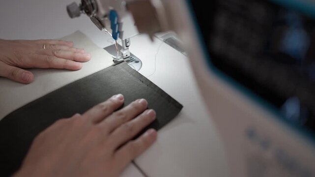 Expert hands skillfully guide a sewing machine, stitching together leather pieces with care. Each movement showcases dedication and artistry in crafting something unique.
