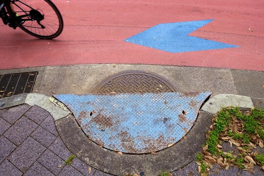道のマンホールと矢印と自転車の後輪