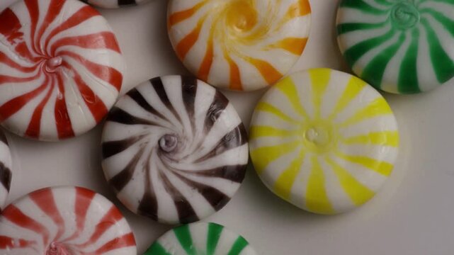 Colorful peppermint swirl candies rotating on white surface