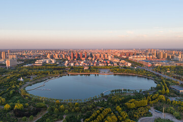 Obraz premium Aerial sunset cityscape with urban lake and green park