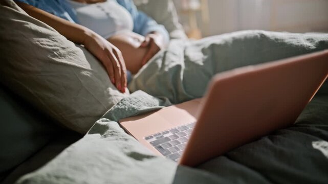 Happy mom-to-be video call laptop bedroom. Close up finger touching trackpad.