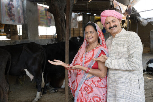 Indian rural couple starting new dairy farm business while standing on dairy farm. Concept of New startup dairy business