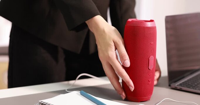 Woman turning on portable audio speaker at table indoors. closeup