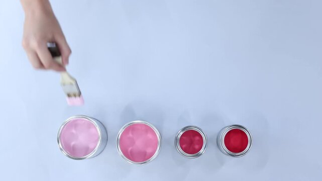 Woman painting with different paints and brush on white background, top view