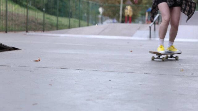 Woman riding skateboard in skate park, closeup. Slow motion effect