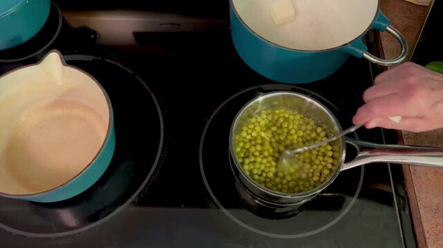 Person stirring green peas in a saucepan on a stovetop