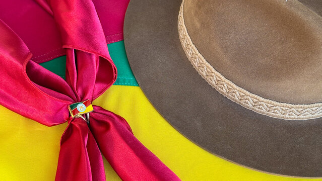 A hat and a gaucho neckerchief resting on the flag of the state of Rio Grande do Sul, Brazil. Farroupilha Week, Gaucho Day.