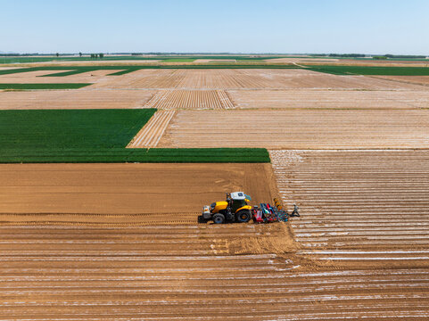 In spring, farmers use farm machinery to grow peanuts，Aerial photos of farmers using agricultural machinery to cultivate the land.