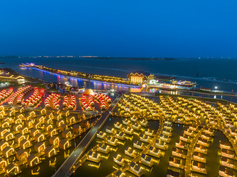 Coastal Water Cottages at Dusk.As twilight falls, rows of water cottages glow with warm lights beside the calm sea.