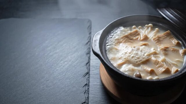 Simmering soy milk hot pot tonyu nabe with fresh yuba tofu skin and mushrooms in clay pot